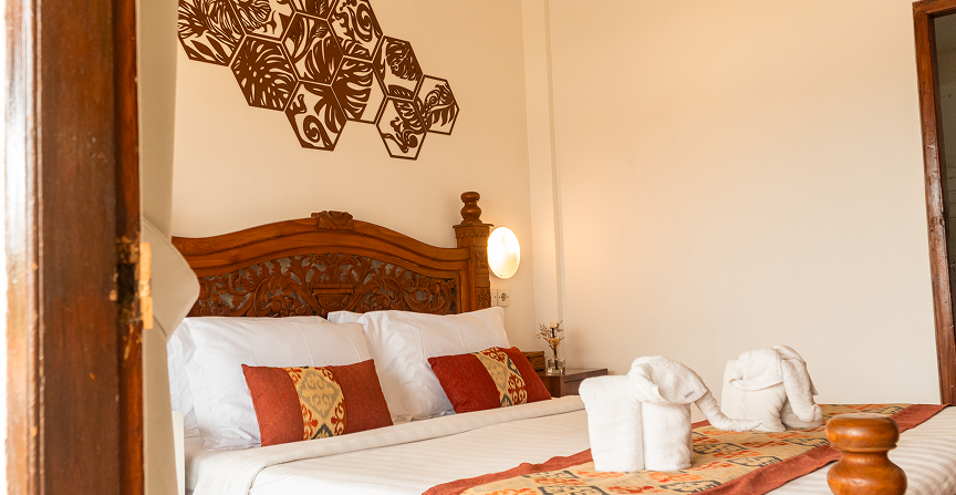 Family Room bed with carved wooden headboard and folded towel elephants